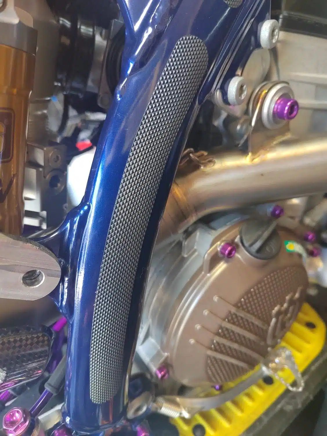 Black grip tape applied to a blue frame of a dirt bike with engine exposed